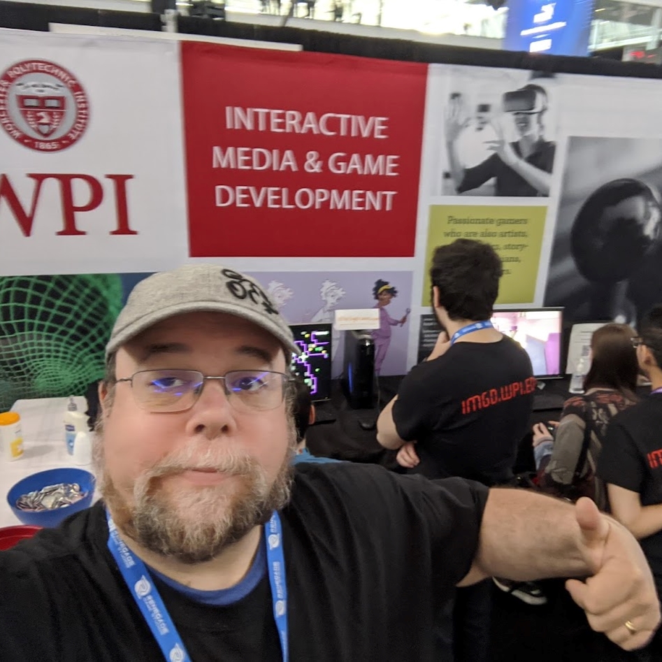 Dean O'Donnell posing in front of the WPI PAX East Booth, 2020